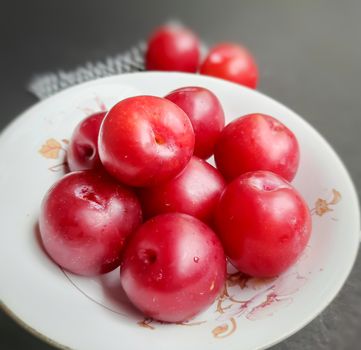 Colorful Red plums kept in bowl placed in white and black background and reduce the risk of cancer heart disease and diabetes