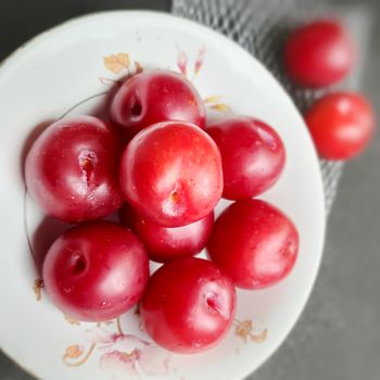 Colorful Red plums kept in bowl placed in white and black background and reduce the risk of cancer heart disease and diabetes