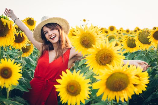 happy woman with red dress and hat in field of sunflowers