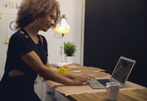 A young fashion designer on her atelier working with a laptop