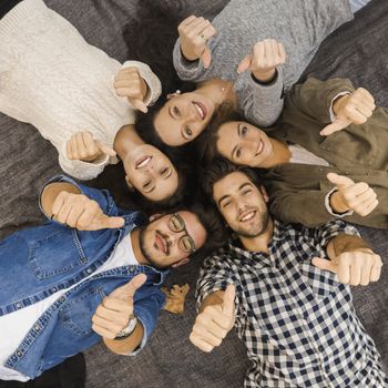 Top view of a group of friends lying on floor and looking at camera