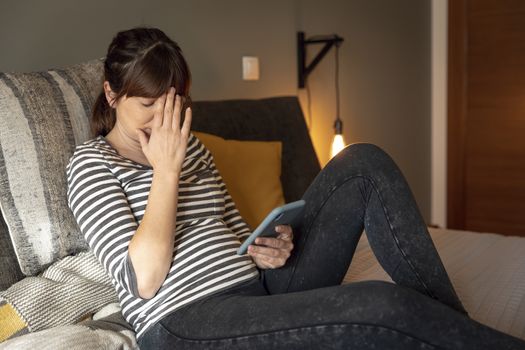 Woman on bed at phone with symptoms of depression