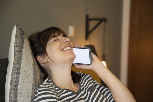 Woman on her bedroom, having a great chat at phone