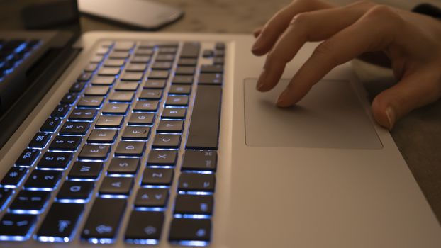 Couple relationships and dating in modern times concept: closeup of woman's hands typing on laptop keyboard in low light ambient