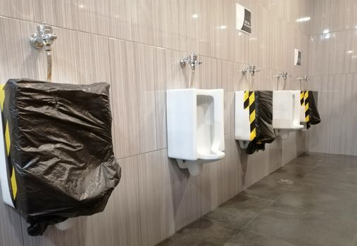 Public men toilet during Corona virus pandemic. New normal that people need to keep social distance to prevent  from virus spread. Personal hygiene, safety and healthcare concept.