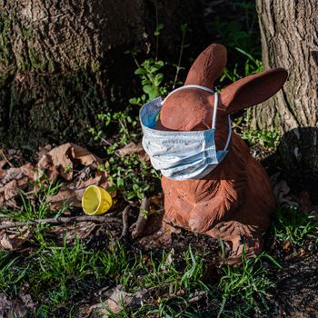 An Easter Bunny ironically placed by a tree is outfitted with a medical mask designed to protect against COVID19.