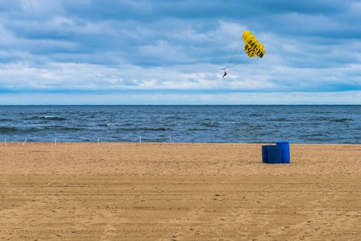 Belmar, NJ, USA -- July 25, 2017. Photo of a parasailer soaring over the Atlantic Ocean using a bright yellow parachute.