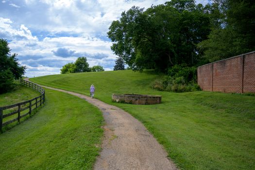 Montpelier, VA, USA -- June 13, 2019. Wide angle of a woman walking along a trail at the estate of James Madison in Montpelier, VA.