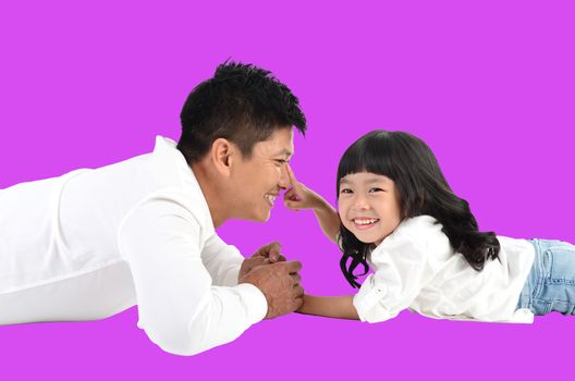 Happy father's day! joyful young dad  playing with  his cute daughter and lying on floor at home. Isolated on purple background.