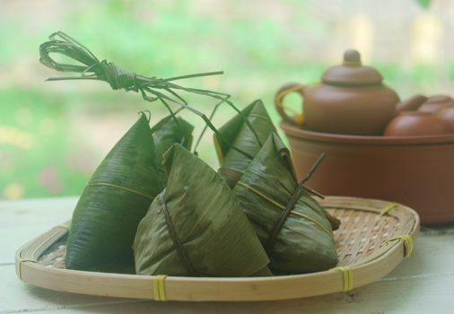 Chinese tradition food - Chinese Steamed Rice Dumpling  with green background outdoor.Zongzi or traditional chinese sticky rice dumpling usually taken during festival occasion. 