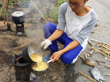 Cooking nodles at outdoors in black pot at picnic on fire