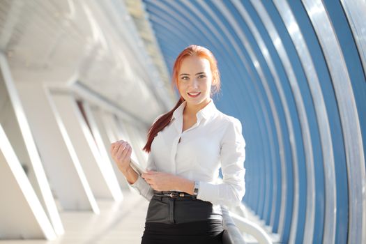 Beautiful redhead businesswoman holding tablet computer inside modern building