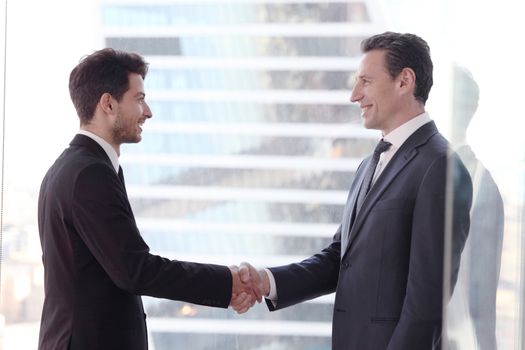 Business people shaking hands by the window in office