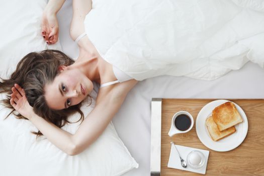 Beautiful young girl having breakfast in bed