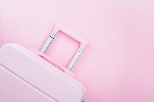 Pinky luggage on pink pastel colored background for traveling concept