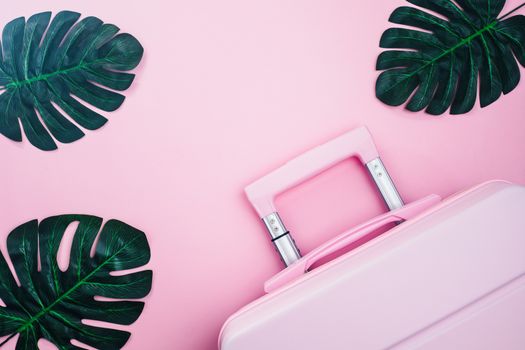 Pinky luggage with palm leaves on pink pastel colored background for traveling concept