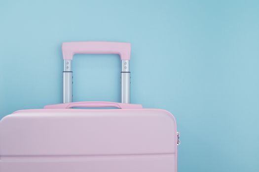 Pink luggage on blue pastel colored background for traveling concept