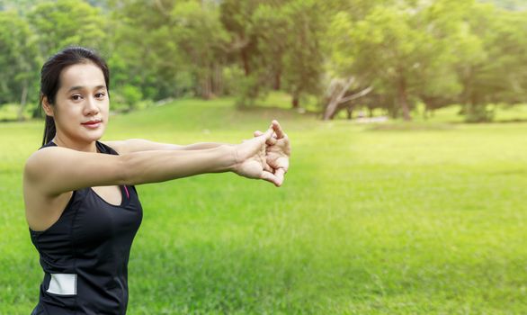 Young asian girl stretching their muscles before jogging outdoors, warming up for morning workout, sitting on path in park. Healthy young asian women warming up before running in park with copy space.