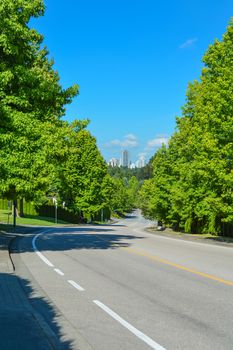 Suburban asphalt road curve leading to a city