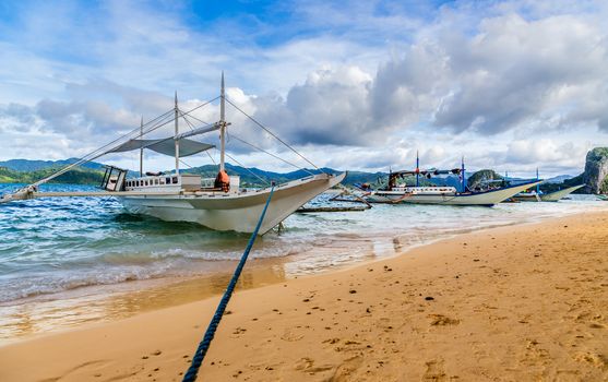 Tropical island landscape with bangca traditional phillipinians boats anchored at the shore, Palawan, Philippines