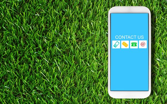 Website and internet contact us concept, customer service, mobile phone on green grass background