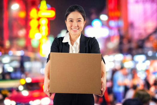 A young woman carrying a box on night market background