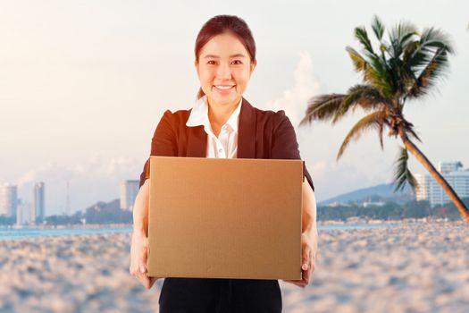 A young woman carrying a box on the beach background