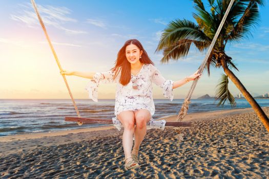 Beautiful woman sitting on a swing on the beach  in Koh Phangan, Thailand