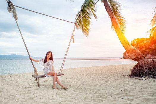 Beautiful woman sitting on a swing on the beach  in Koh Phangan, Thailand