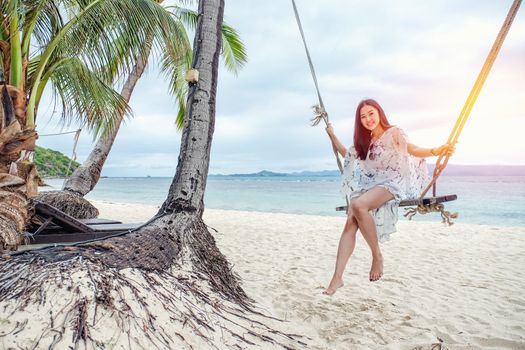 Beautiful woman sitting on a swing on the beach  in Koh Phangan, Thailand