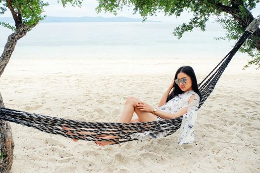 Beautiful woman sitting on a swing on the beach  in Koh Phangan, Thailand