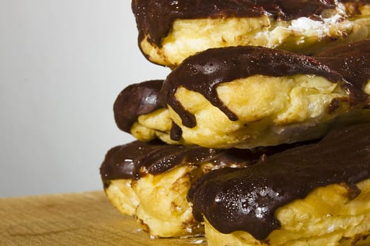 Eclairs with chocolate icing on a wooden table