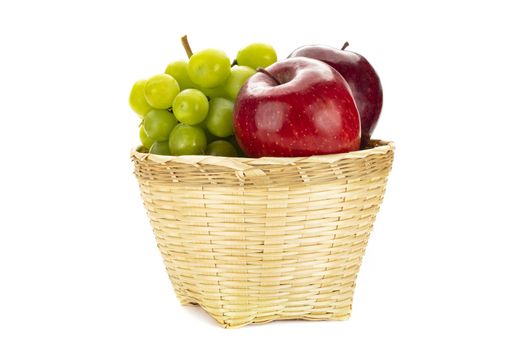 A bunch of green grapes and red apples in a weave bamboo basket. Isolated on white background.