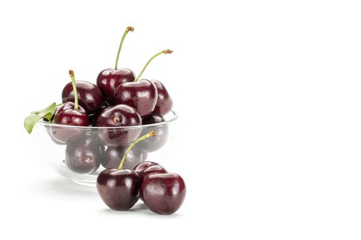 A bunch of ripe red cherries in a clear glass cup. Isolated on white background.