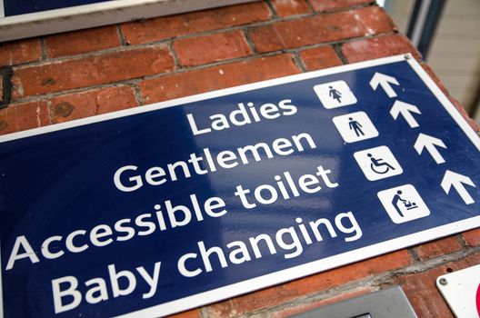 Sign showing directions to public toilets on a brick wall.  