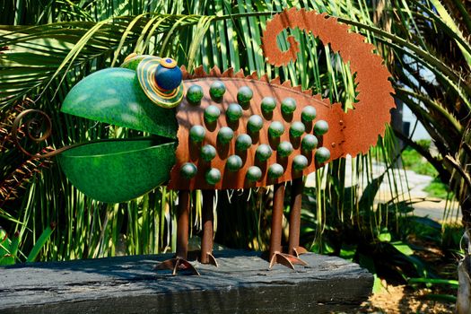 Funny garden sculpture representing a chameleon. Glass and rusty metal as its building elements.