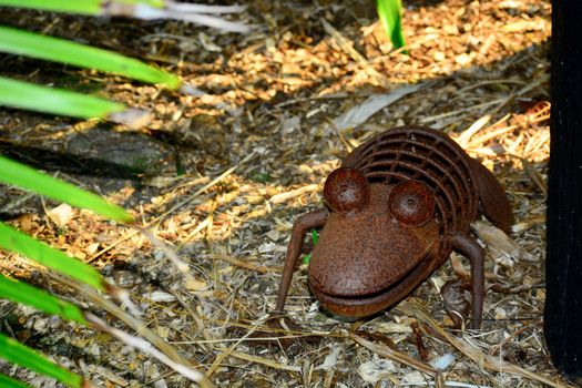 Peculiar modern sculpture made of rusty wire and some metal parts, representing a small crocodile hiding in the grass.