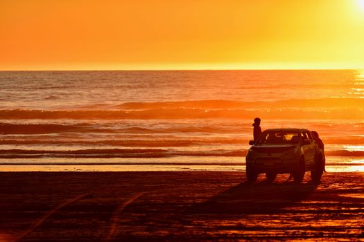 Unidentified people enjoying sunset on a beach.