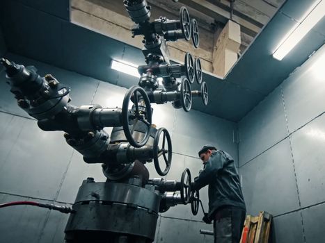 Assembling a well at the oil equipment plant. The connection of the valves and other well parts in the assembly hall.