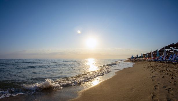 Landscape with sunbeds and umbrella on the sea, beach at sunrise