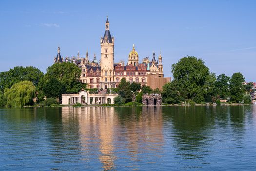Landscape photo of Schwerin Palace with the castle image partially reflected in the lake.