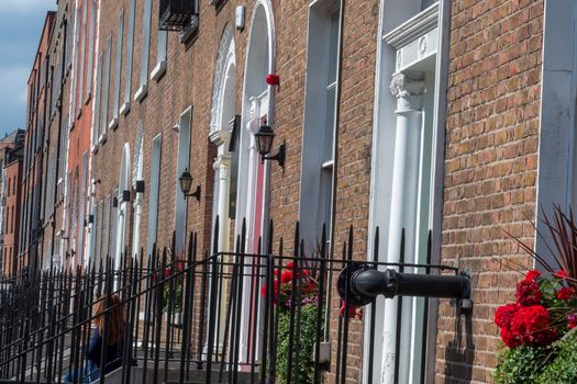 Dublin, Ireland -- July 9, 2018. A red haired woman is sitting on the stoop of a flat that is part of  a row of flats in Dublin, Ireland.