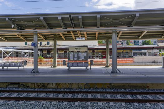 Day view of Stathmos Larisis railway platforms area with waiting seats, Athina sign and background station building view.
