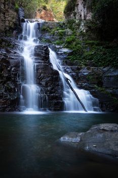 Fresh clean water flowing over the cliff ledge waterfall tumbling into a beautiful swimming hole in lush Australian wilderness