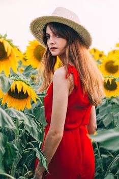 woman with red dress and hat in sunflowers field.