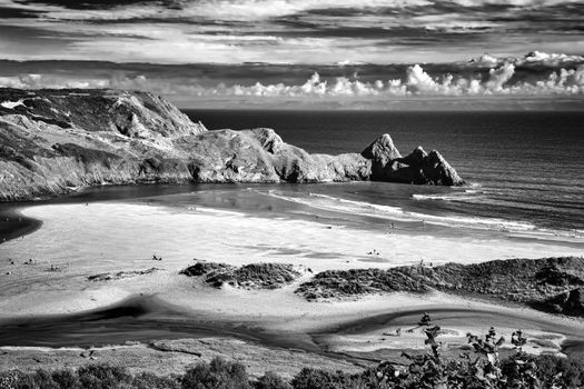 Three Cliffs Bay beach on the Gower Peninsular West Glamorgan Wales UK, which is a popular Welsh coastline travel destination of outstanding beauty black and white monochrome stock image