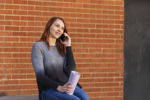 A gorgeous blonde model enjoys a winters day outdoors while drinking her favorite drink and talking on her cellphone