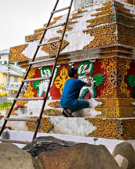 Artist painting with bright colours pagoda in Manali, Himachal Pradesh, India.