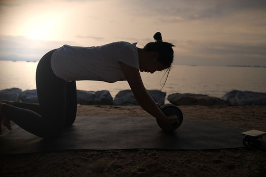 The silhouette of a beautiful woman practicing yoga on the beach during the red and orange summer sunset.