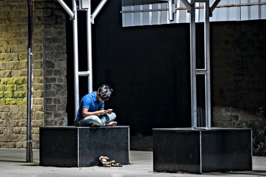 Udupi, Karnataka, India:January 30th, 2019 - Youth engrossed in his cell phone on railway platform.